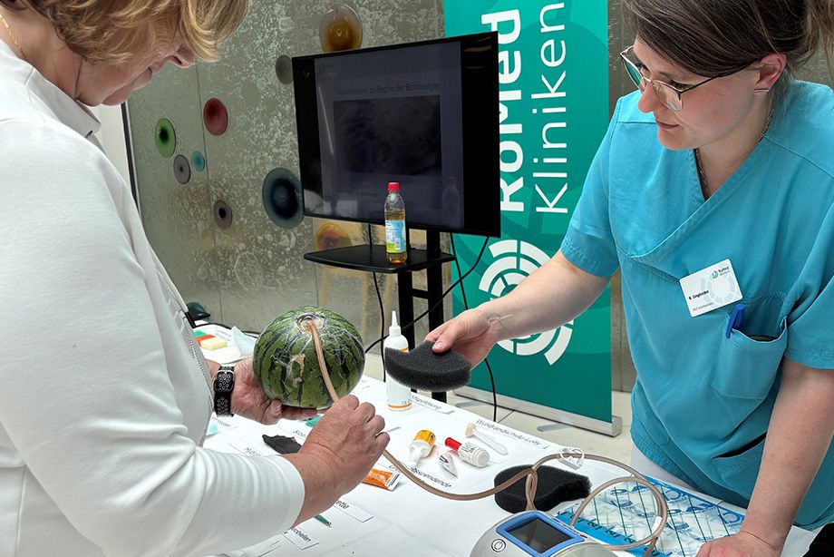 Anschauliche Demonstration: Mithilfe einer Wassermelone erklärt die Wundexpertin einer Besucherin die VAC-Therapie, bei der durch kontrollierten Unterdruck Wundsekret abgesaugt und die Wundheilung gefördert wird. Anschauliche Demonstration: Mithilfe einer Wassermelone erklärt die Wundexpertin einer Besucherin die VAC-Therapie, bei der durch kontrollierten Unterdruck Wundsekret abgesaugt und die Wundheilung gefördert wird.